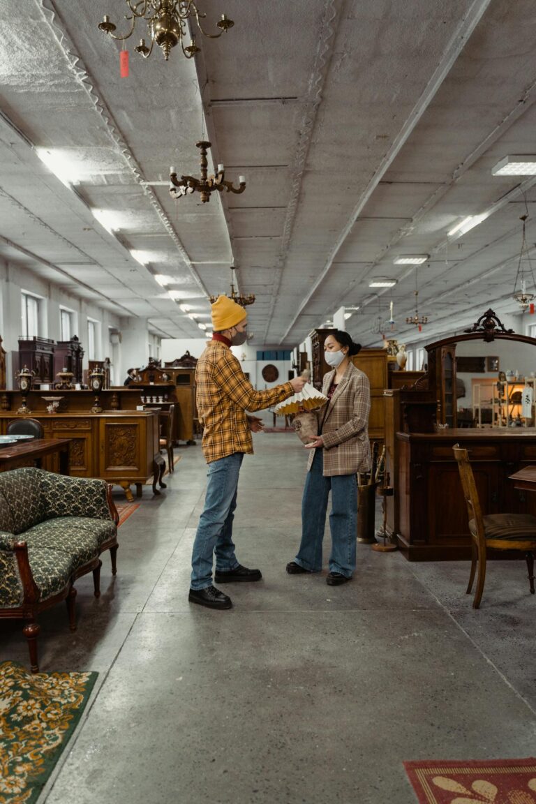Two young adults in a vintage warehouse inspecting furniture. Retro interior.